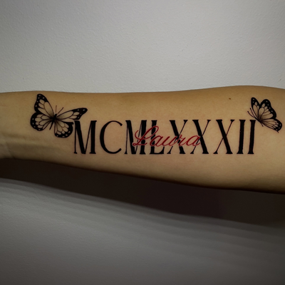 Her moms name and birth year (Laura 1982) Roman numerals — tattoo by Jc TheArtist, Downey, California