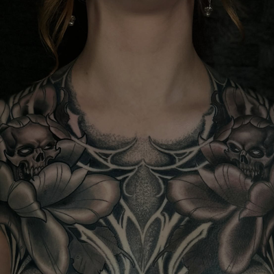 Twin skulls tucked into peonies, dark ornamental filigree running down the stern… — tattoo by Dorian Perches, Banning, California